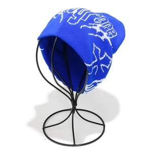 Detail of royal blue knit beanie with white gothic lettering and cross jacquard