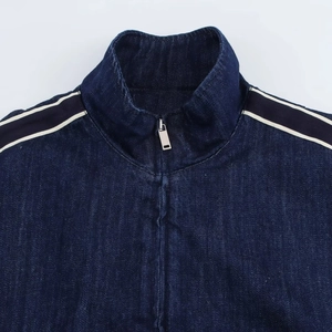 Dettaglio del collo alto e zip in metallo su giacca in denim con nastri a righe