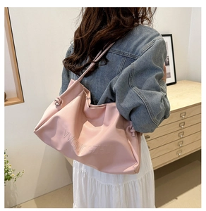 Detail of soft pink PU leather tote bag with embossed text and elegant knotted shoulder strap