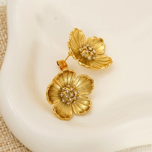 Macro view of gold flower earrings with petal textures and shimmering center crystals