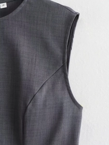 Detail of dark grey sleeveless dress showing round neck and high-quality woven texture