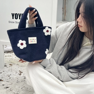 Detail of navy plush tote bag with white flower embroidery and woven brand label