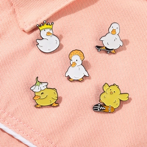 Set of five cute cartoon enamel pins with duck designs pinned to pink denim jacket