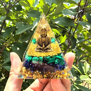 Macro detail of resin pyramid with golden Buddha, malachite, and lapis lazuli in sunlight