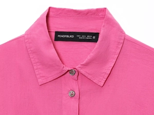 Close-up detail of fuchsia pleated shirt buttons and the collar brand label