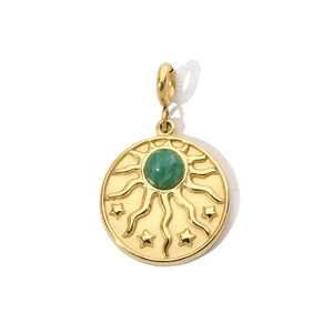 Dettaglio del ciondolo sole boho in oro con gemma verde e rilievo a stella su sfondo bianco