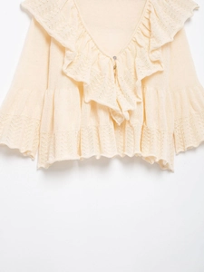 Detail of V-neck knit cardigan featuring elegant ruffle trim and lace crochet textures