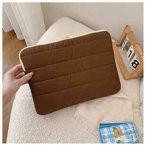 Detailed close-up of dark brown quilted puffer laptop sleeve with horizontal stitching