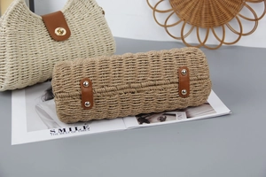 Detail of khaki woven straw bag with brown leather bottom reinforcement and rivets