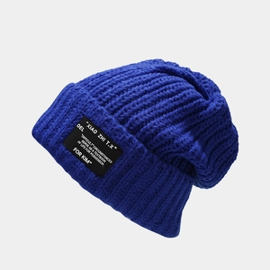 Detail van de Klein blauwe ribgebreide beanie met een vintage patch met letters erop