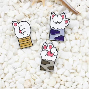 Three cute alloy cat paw enamel pins with various patterns on white pebble background