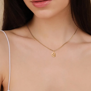 Primo piano della collana a catena cubana in acciaio inossidabile dorato con lettera G