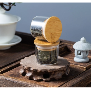 Close-up of portable mini glass tea jars with bamboo lids on a wooden base