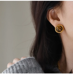 Close-up of vintage golden twisted rope earrings with round tiger eye stones on model