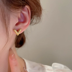 Gros plan d'un clou d'oreille en V doré porté par un mannequin féminin