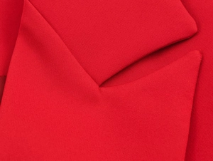 Macro detail of red blazer fabric showing collar stitching and smooth textile texture
