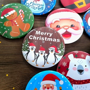 Customizable Christmas tinplate badges featuring Santa and gingerbread man on wooden surface