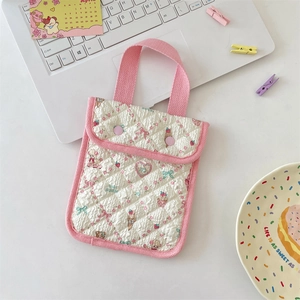 Detail view of quilted floral doll house mini handbag on a desk with cute stationary
