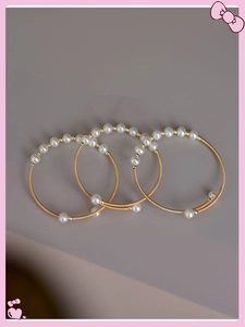 Close-up of three gold-plated pearl bracelets with spiral wire and white beads