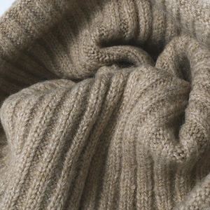 Close-up of thick camel wool knit texture and ribbed pattern on winter beanie hat