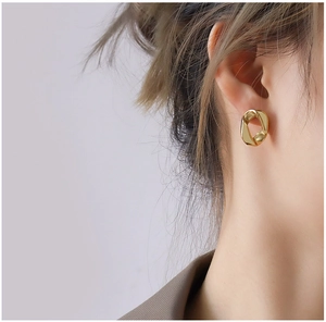 Détail de boucles d'oreilles créoles torsadées plaquées or 18 carats sur un mannequin