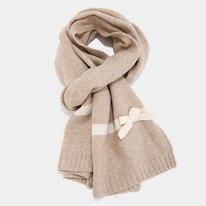 Detail of soft knit scarf featuring contrast stripes and a delicate 3D bow decoration