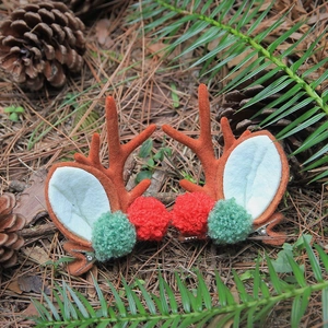 Barrettes bois de renne de Noël avec pompons rouges et verts sur un fond de forêt naturel