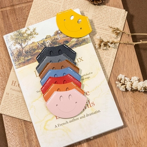 Colorful leather smile face bookmarks stacked on books in a cozy lifestyle setting