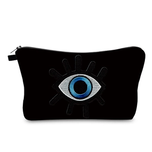 Close-up of black evil eye cosmetic bag with blue embroidery and silver zipper detail
