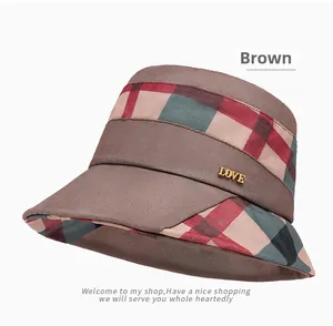 Detail of elegant brown plaid bucket hat featuring a gold LOVE metal accessory