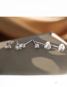 Macro shot of silver heart-shaped zircon stud earrings in various sizes with high polish