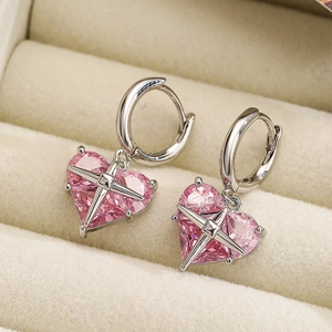 Macro shot of pink heart-shaped crystal earrings with star-claw setting on beige box