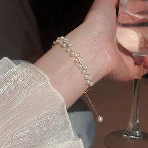 Gros plan d'un élégant bracelet double rang de perles dorées porté par une femme