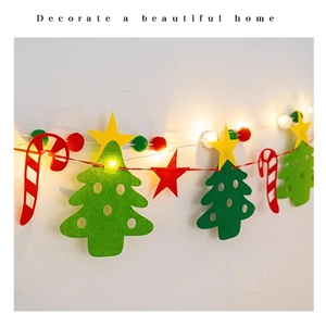 Close-up of felt Christmas tree and candy cane banner decorations with warm LED string lights