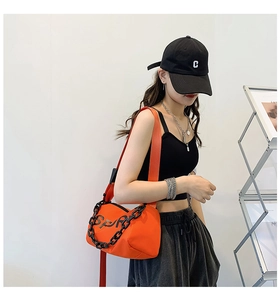 Détail du sac à bandoulière en nylon orange vif avec chaîne noire et lettrage SP sport