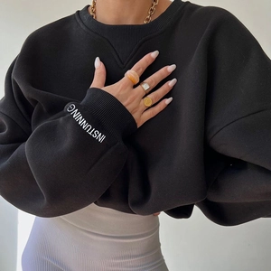 Detail of black knitted sweatshirt showing V-stitch neckline and INSTUNNING sleeve print