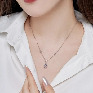 Elegant silver necklace with pear-cut zircon and round diamonds on a silk shirt