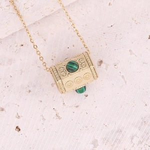 Macro detail of gold cylinder pendant with scroll relief and green malachite gemstone