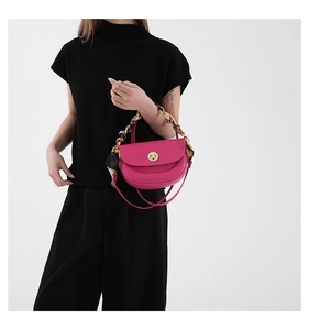 Detail of fuchsia saddle bag with silk ribbon handle and gold lock on model