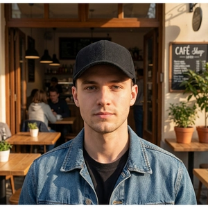 Detail of black herringbone baseball cap with thick texture worn in outdoor cafe setting