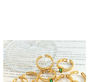 Detail of gold braided rings featuring green and clear rectangular gemstones