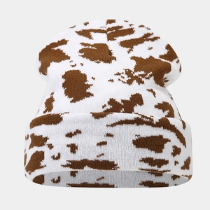 Close-up of tight knit texture and brown cow print pattern on a white winter beanie hat