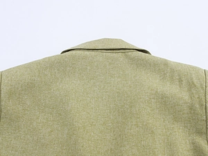 Close-up of the shoulder stitching and light green linen fabric texture on the two-piece suit