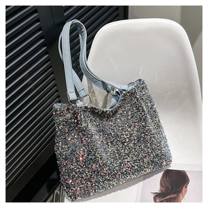 Detail of silver sequined tote bag featuring light blue straps on a minimalist chair