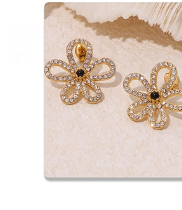 Detail of gold floral stud earrings with black center gems and sparkling clear zircons