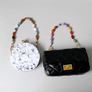 Detail of colorful beaded handles on marble acrylic and black quilted leather handbags