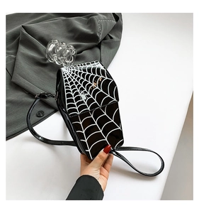Close-up of black patent leather spider web shoulder bag with white graphic details