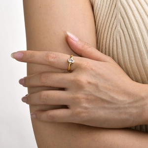 Close-up of a minimalist gold ring featuring a white oval-cut gemstone on a finger