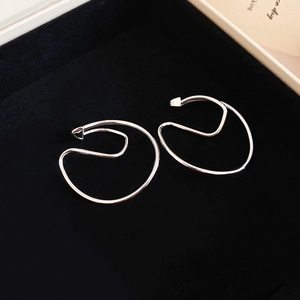 Detailed view of silver minimalist geometric ear clips on a black velvet display tray