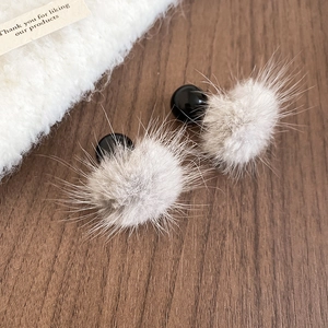 Gros plan de boucles d'oreilles pompon en fourrure grise avec perles sur bois